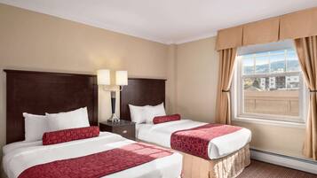 A hotel room with two beds, a nightstand with lamps, and a large window with curtains.