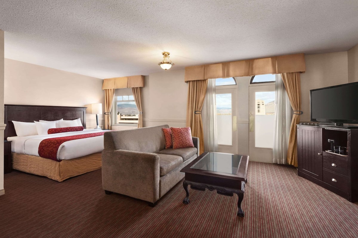 Une chambre d’hôtel avec un lit, un canapé, une télévision et une table en verre.