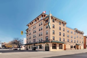 A multi-story hotel with a Canadian flag, featuring a classic architectural style with arched windows and a green awning.
