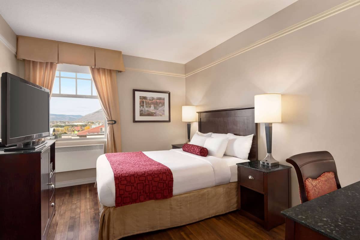 Une chambre d’hôtel avec un lit, une télévision, un bureau et une chaise.