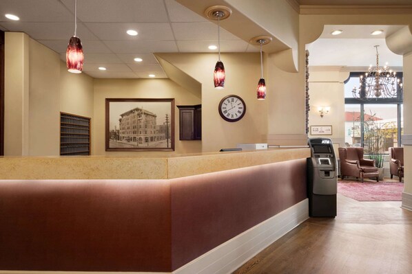 A reception area with a counter, a clock, an ATM, and a framed picture on the wall.