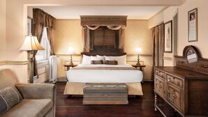 A classic hotel bedroom with a large bed, two bedside tables with lamps, a wooden dresser, and a chair. - The Plaza Hotel Downtown, Trademark Collection by Wyndham (Kamloops)