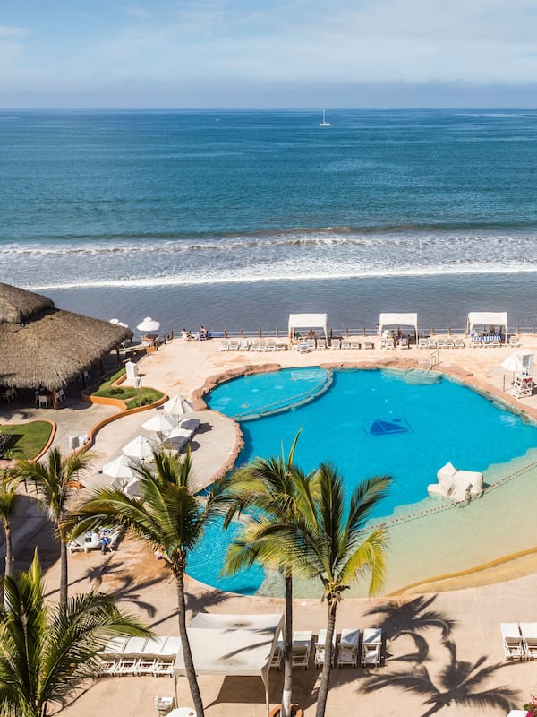 Alberca al aire libre, sombrillas en la alberca y camastros