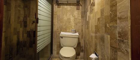 A small bathroom with a toilet, a towel rack, and a shower area.