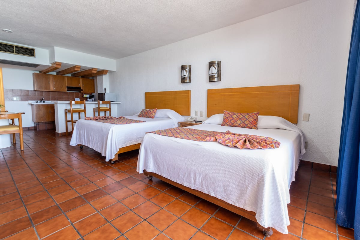 Een hotelkamer met twee bedden, een kitchenette en een eethoek.