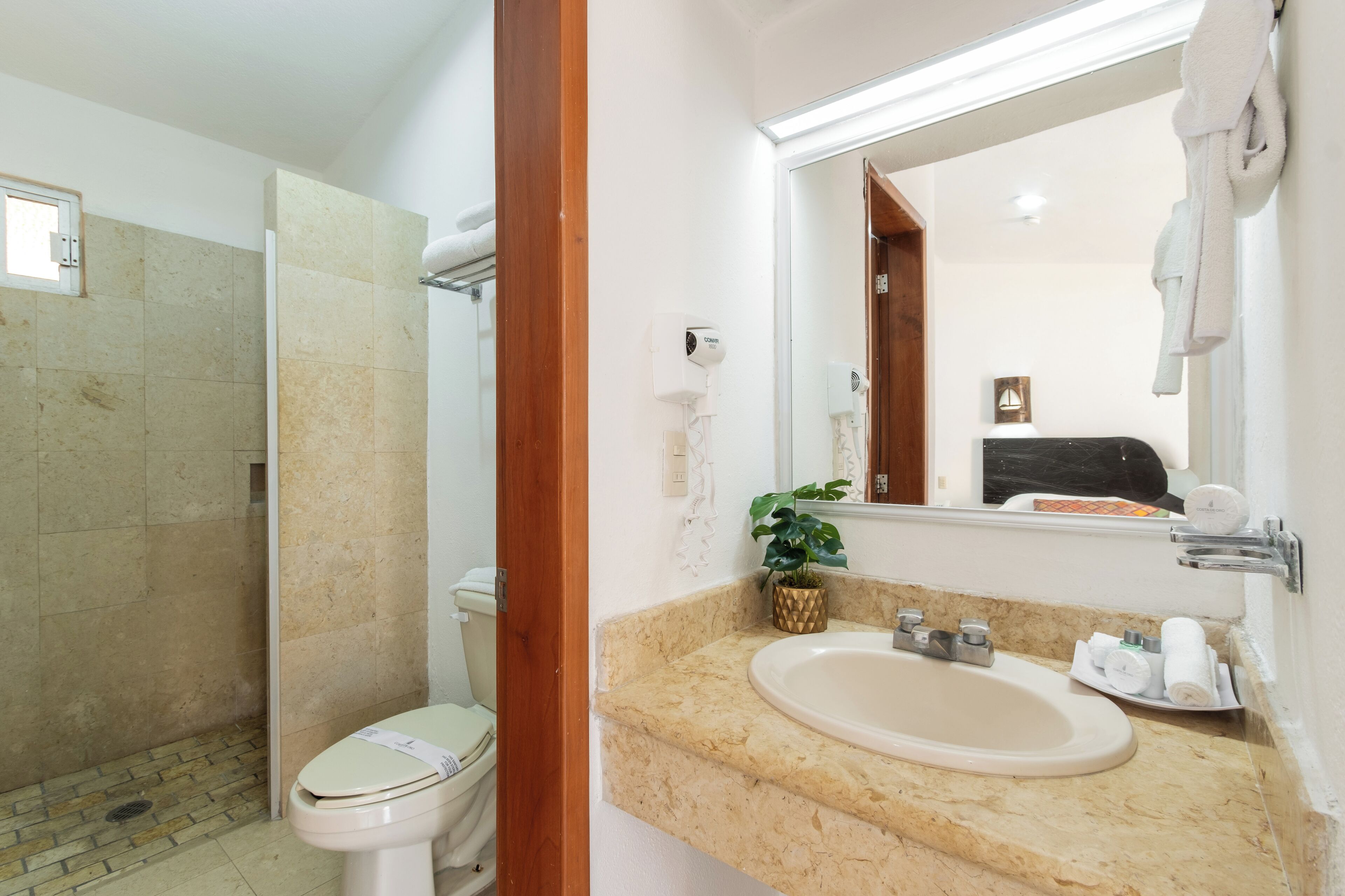 A bathroom with a shower, toilet, sink, and a mirror.