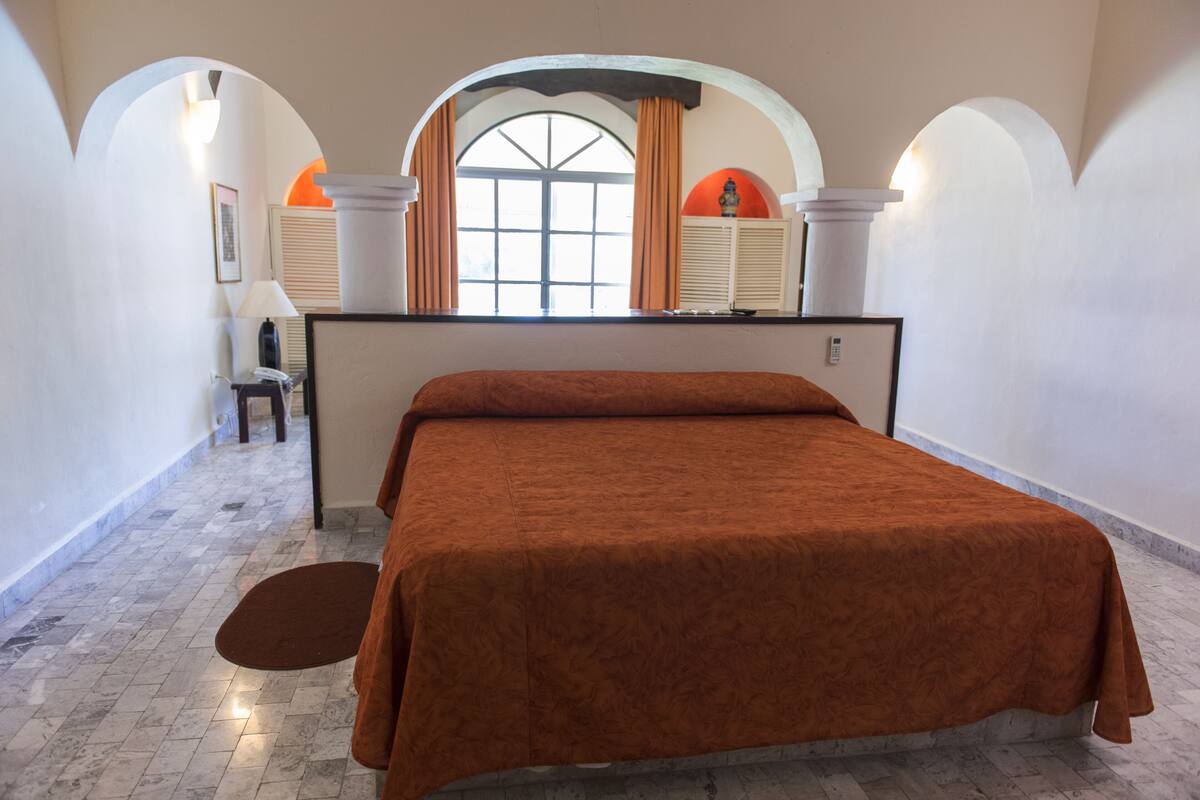 Un dormitorio con una cama grande, una ventana con cortinas y suelo de mármol.