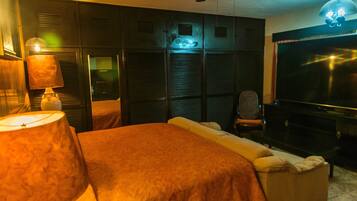 A bedroom with a bed, a chair, a TV, and a ceiling fan.