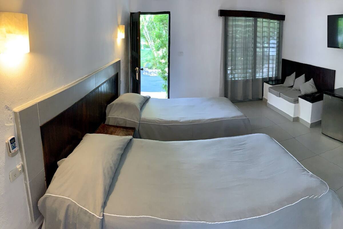 Habitación de hotel con dos camas, un escritorio, un televisor y un baño.
