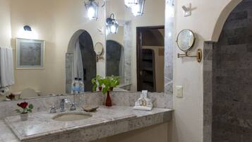 A bathroom with a marble sink, two wall-mounted mirrors, a potted plant, and a framed picture on the wall.