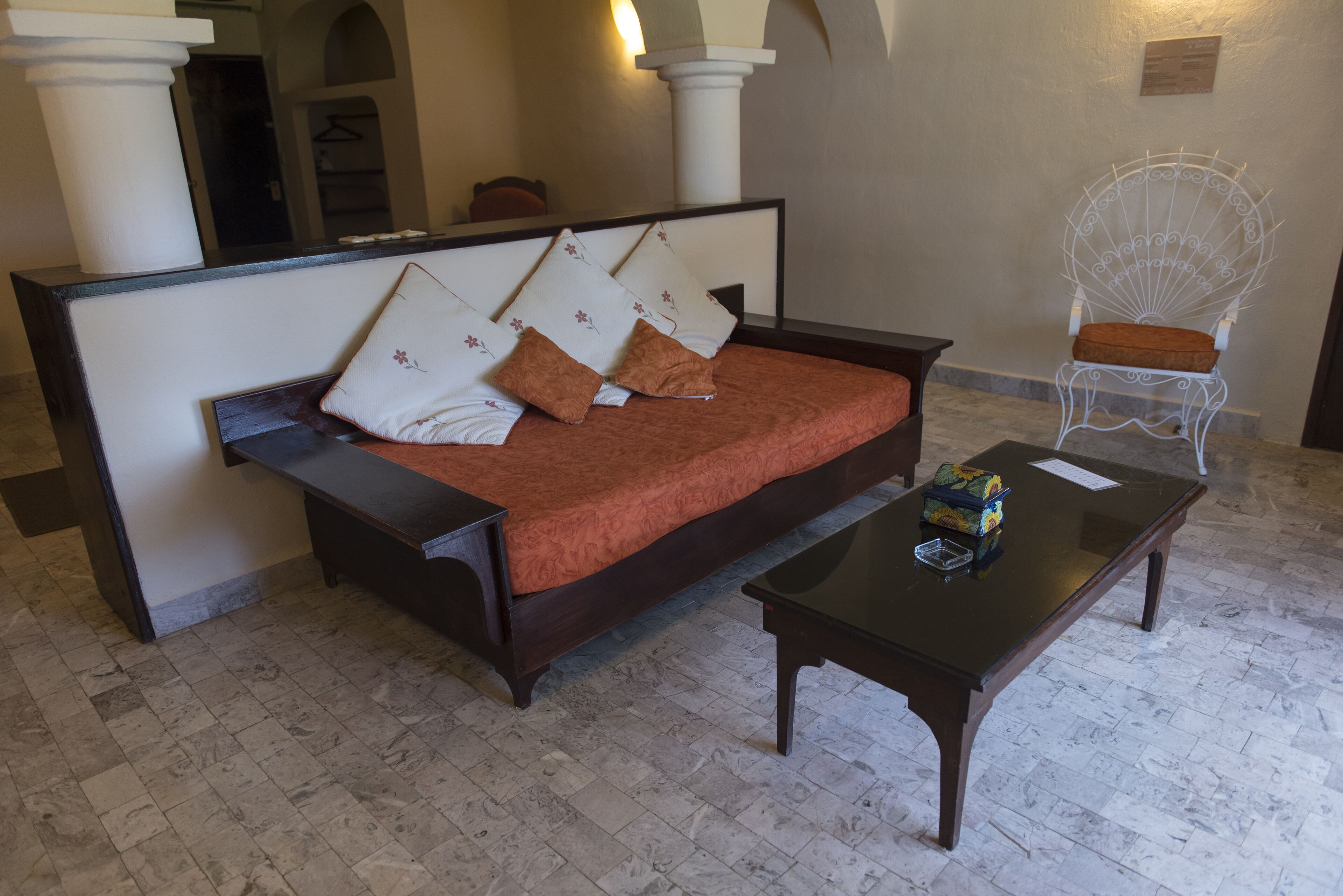 A room with a bed, a wooden nightstand, a chair, and a small table.