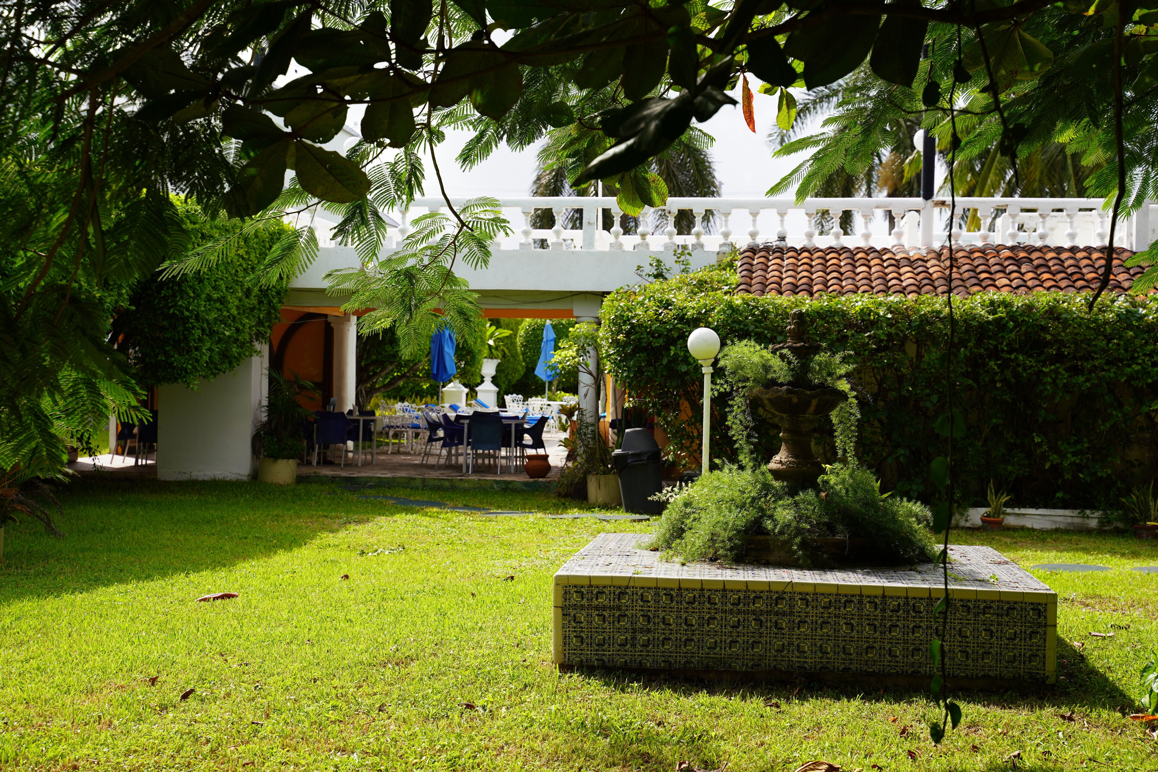 A courtyard with a tiled planter, a white fence, and a building with a tiled roof.