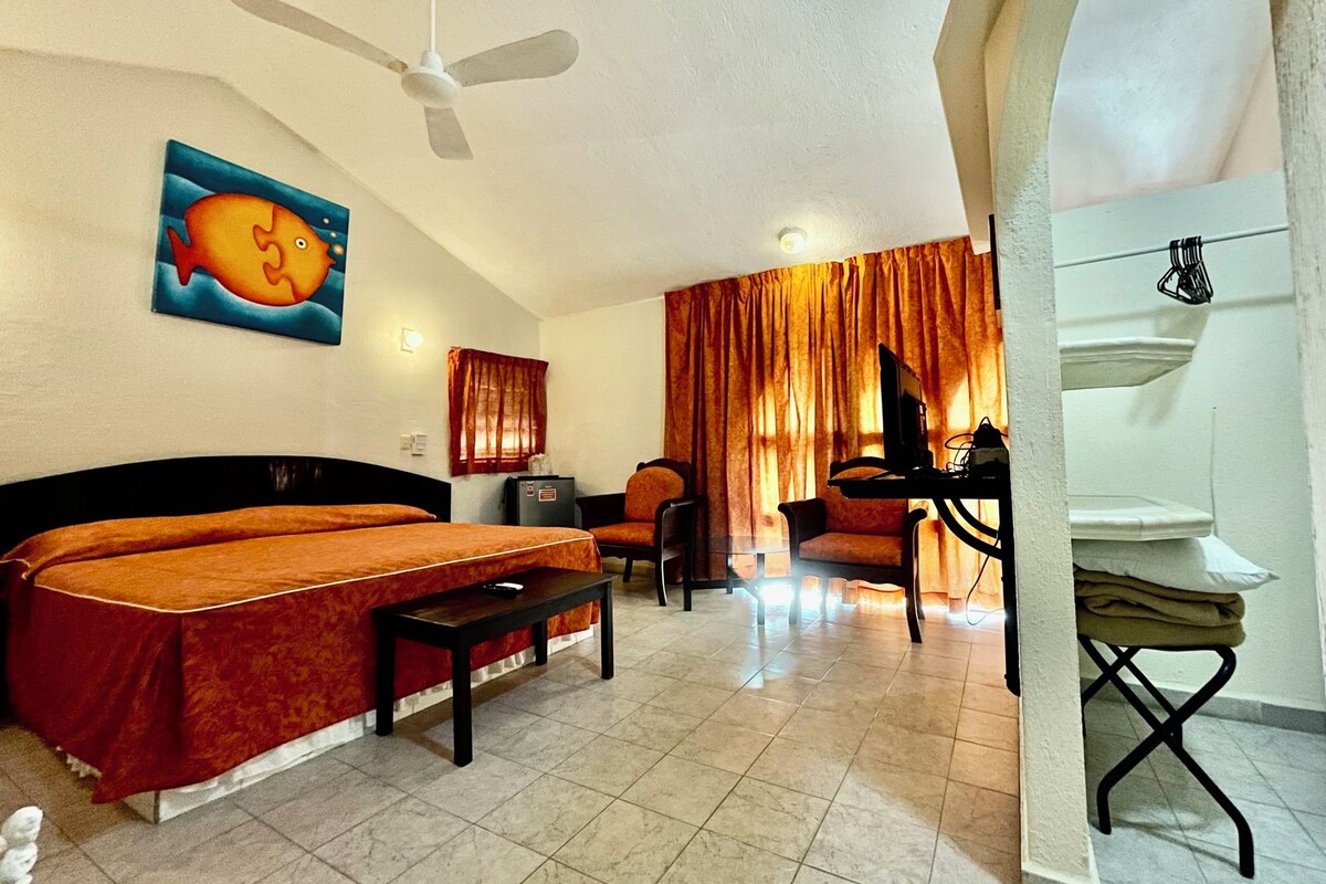 Ein Hotelzimmer mit Bett, Schreibtisch, Stuhl und Deckenventilator.