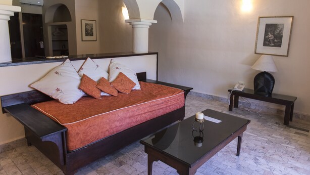 A bedroom with a bed, a bedside table, a lamp, and a fan.