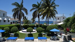 A poolside area with lounge chairs, umbrellas, and palm trees. - Villablanca Garden Beach Hotel (Cozumel)