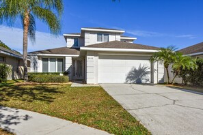 A two-story house with a garage, number 2905, surrounded by a well-maintained lawn and palm trees. - Advantage Vacation Homes (Kissimmee)