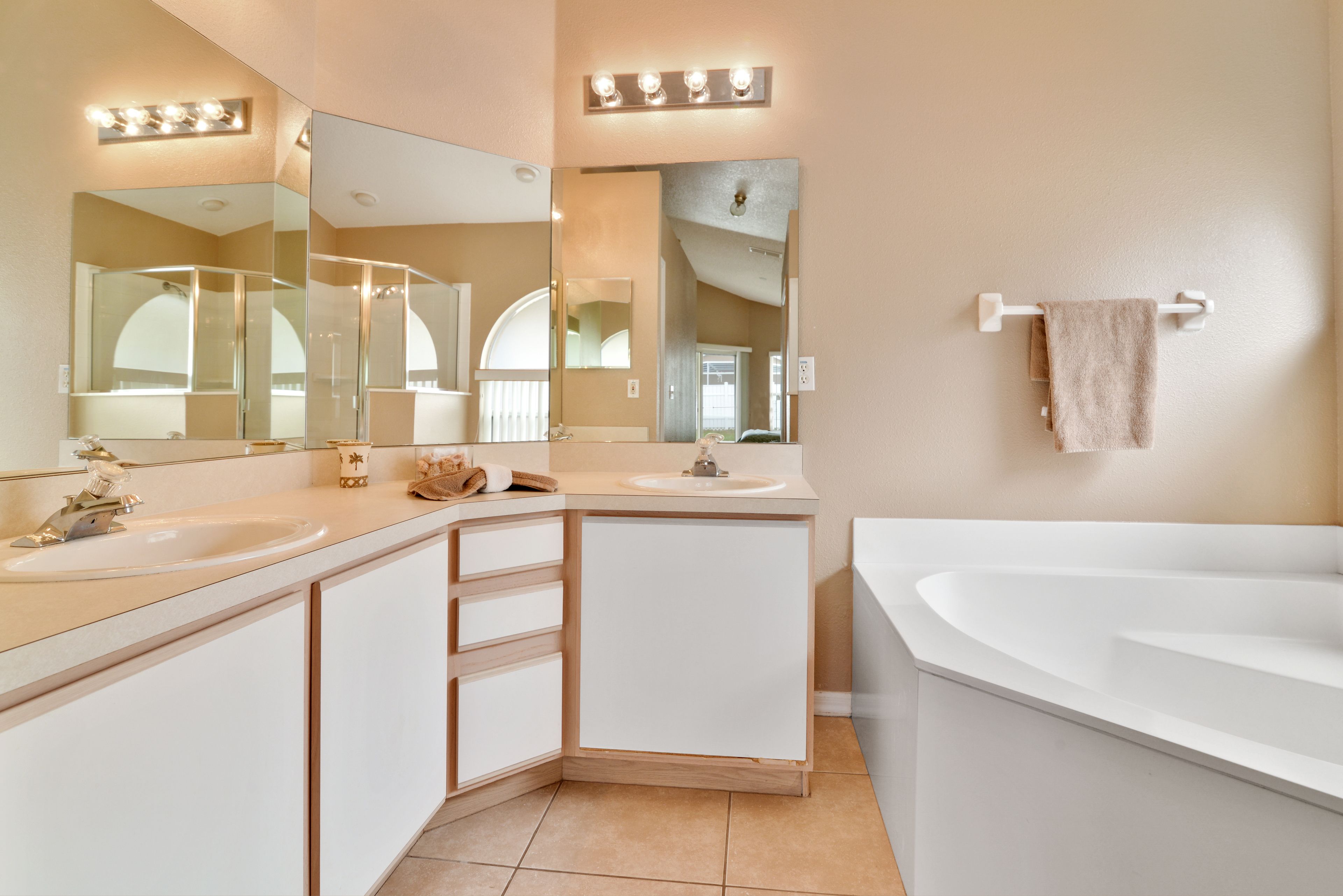 A modern bathroom with two sinks, a large mirror, and a bathtub.
