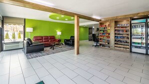 En modern inredning med en grön vägg, lädersoffor, ett soffbord och ett kylskåp fyllt med drycker.