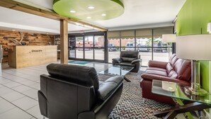 En modern entréhall med lädersoffor, en receptionsdisk och en vägg i en accentfärg.