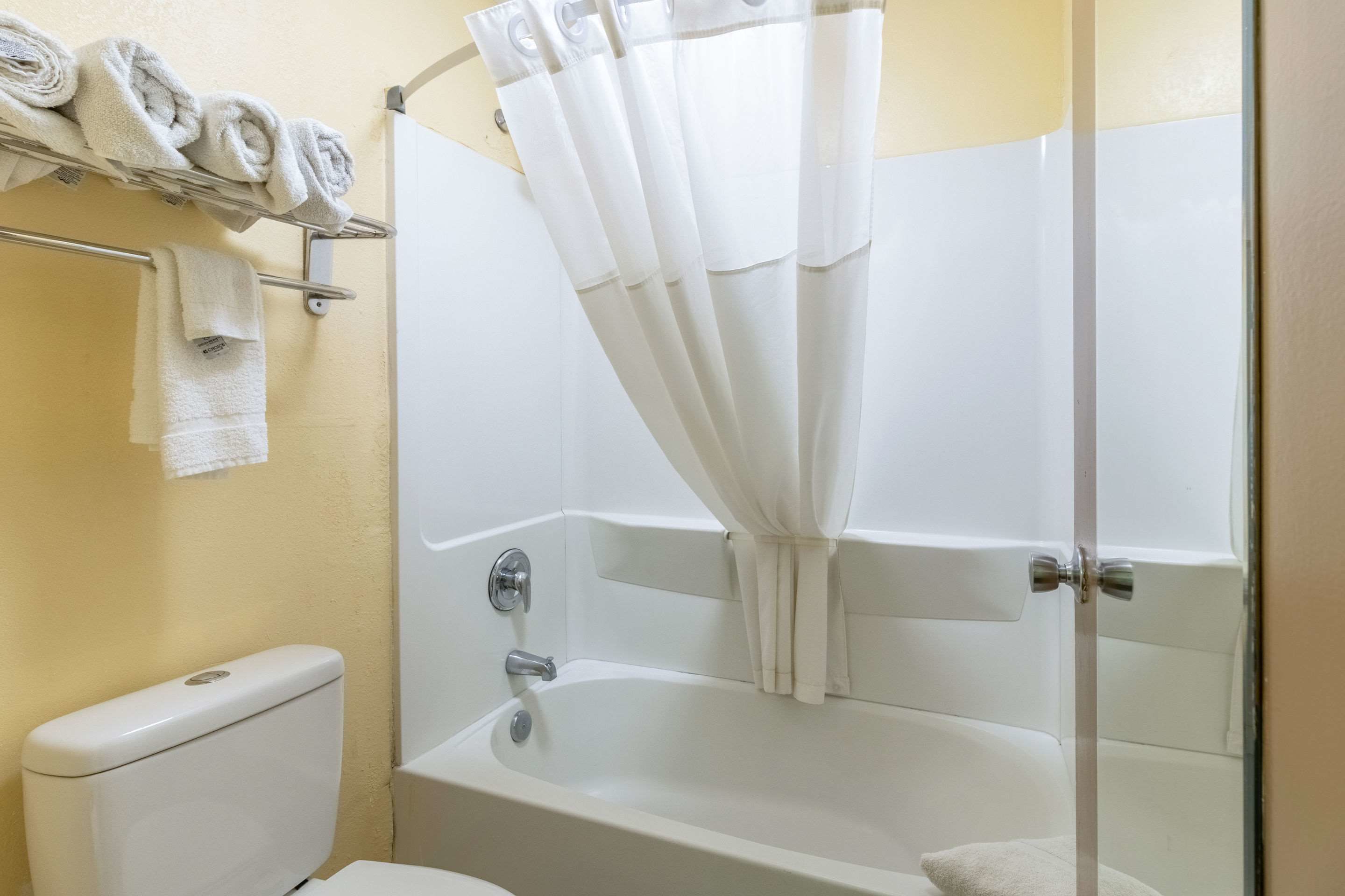 Une salle de bain équipée d’une baignoire, de toilettes et d’un porte-serviettes où sont soigneusement pliées les serviettes.