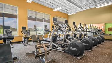 Une salle de sport équipée de plusieurs tapis de course, de machines de musculation et de vélos d’exercice.