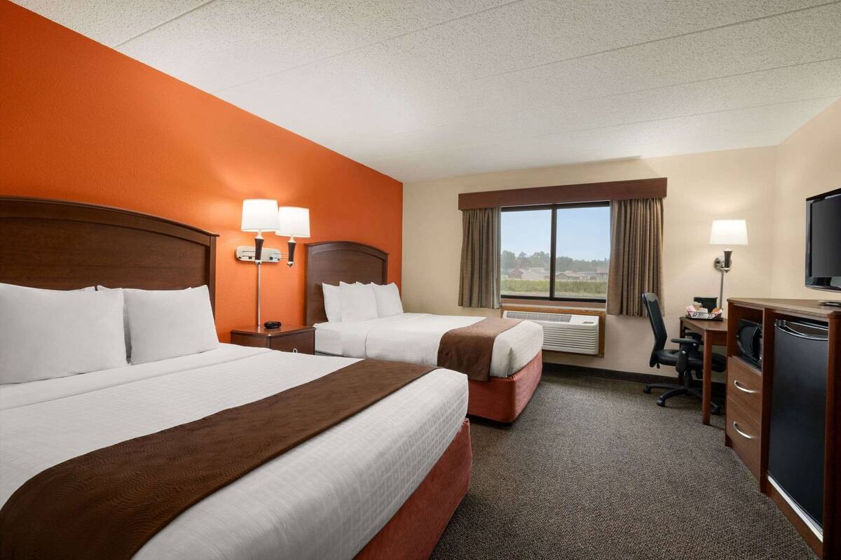 Habitación de hotel con dos camas, un escritorio, un televisor y ventana con vistas.
