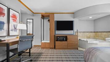 Ein Hotelzimmer mit Bett, Schreibtisch mit Stuhl, Fernseher, Mikrowelle, Schrank, Dusche und Badewanne.