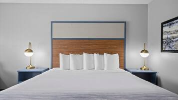 A neatly made bed with a wooden headboard, two bedside tables with lamps, and a framed picture on the wall.