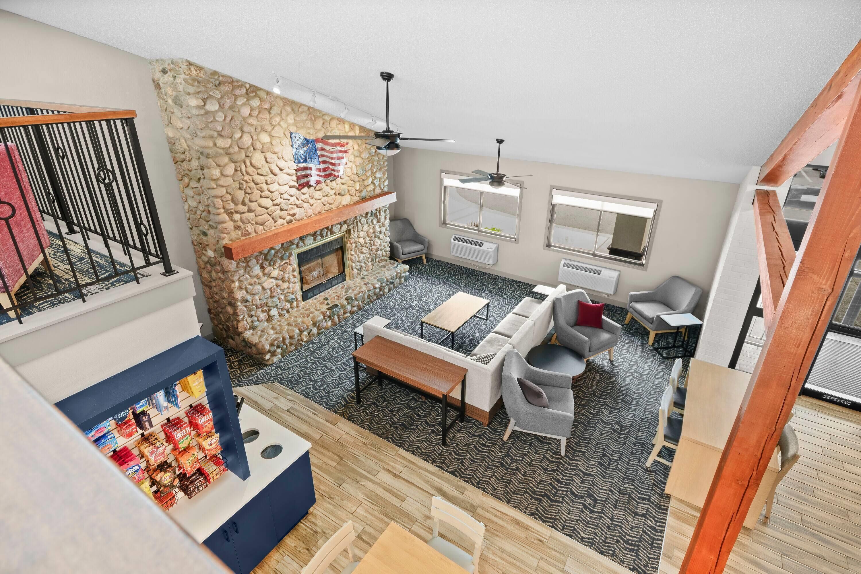 A spacious living area with a stone fireplace, a ceiling fan, and a seating arrangement including a sofa and chairs.