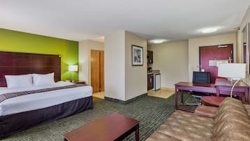 Una habitación de hotel con cama, escritorio, silla, sofá y una pequeña kitchenette.