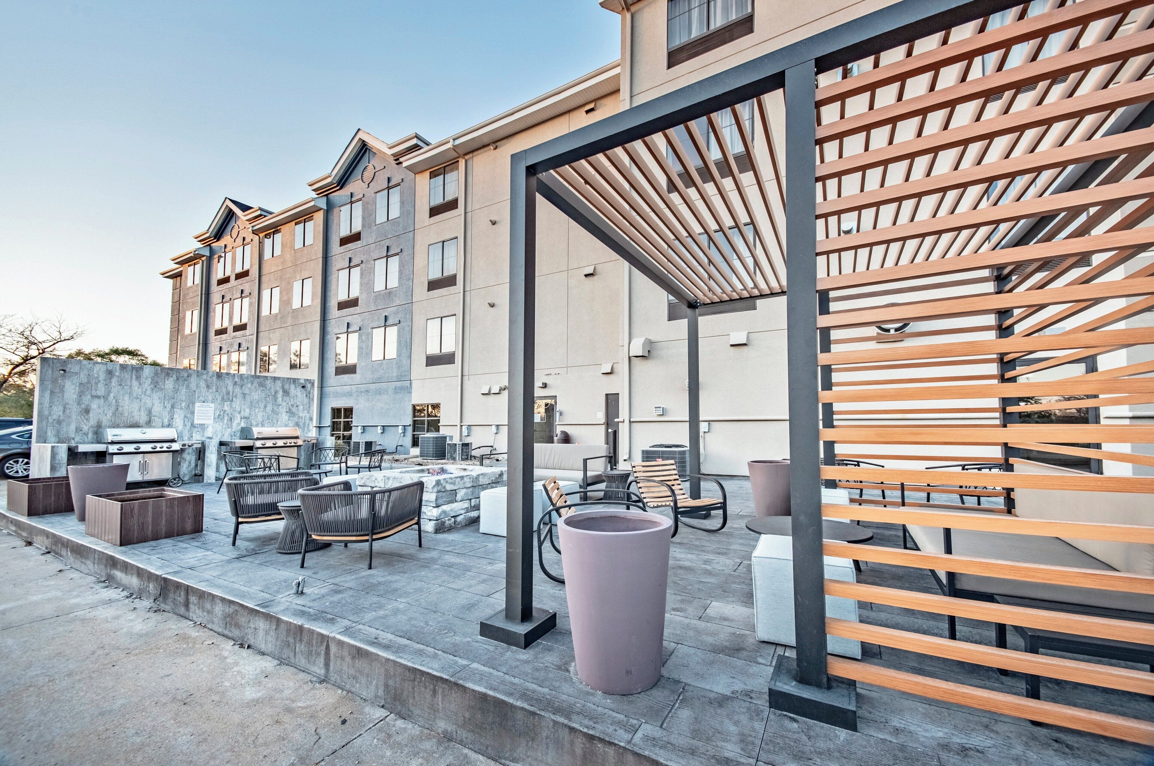 An outdoor patio area with a barbecue setup, seating, and a pergola structure.