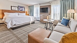 A hotel room with a bed, a sofa, a small table, and a TV. - Staybridge Suites Cedar Rapids North by IHG (Cedar Rapids)