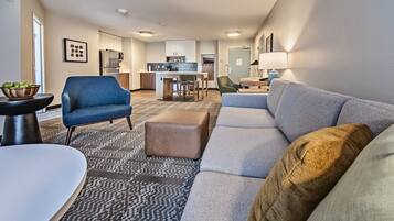 A modern living room with a sofa, ottoman, and a dining table with chairs.