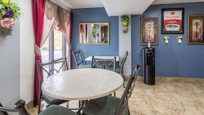 Un comedor con una mesa redonda y sillas, un dispensador de agua y un espejo en la pared.