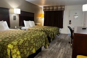 Quarto de hotel com duas camas, uma escrivaninha, uma cadeira e janela com cortinas.
