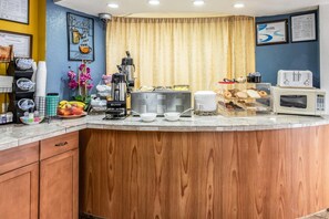 A kitchen area with a coffee station, a microwave, and a food display. - Park Inn by Radisson, Macon North (Macon)
