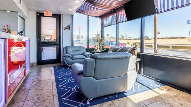 A hotel lobby with a reception desk, seating area, and large windows offering a view of the parking lot. - Park Inn by Radisson, Macon North (Macon)