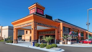 A hotel with a prominent EconoLodge sign, a covered entrance, and a parking lot with a red car. - Park Inn by Radisson, Macon North (Macon)