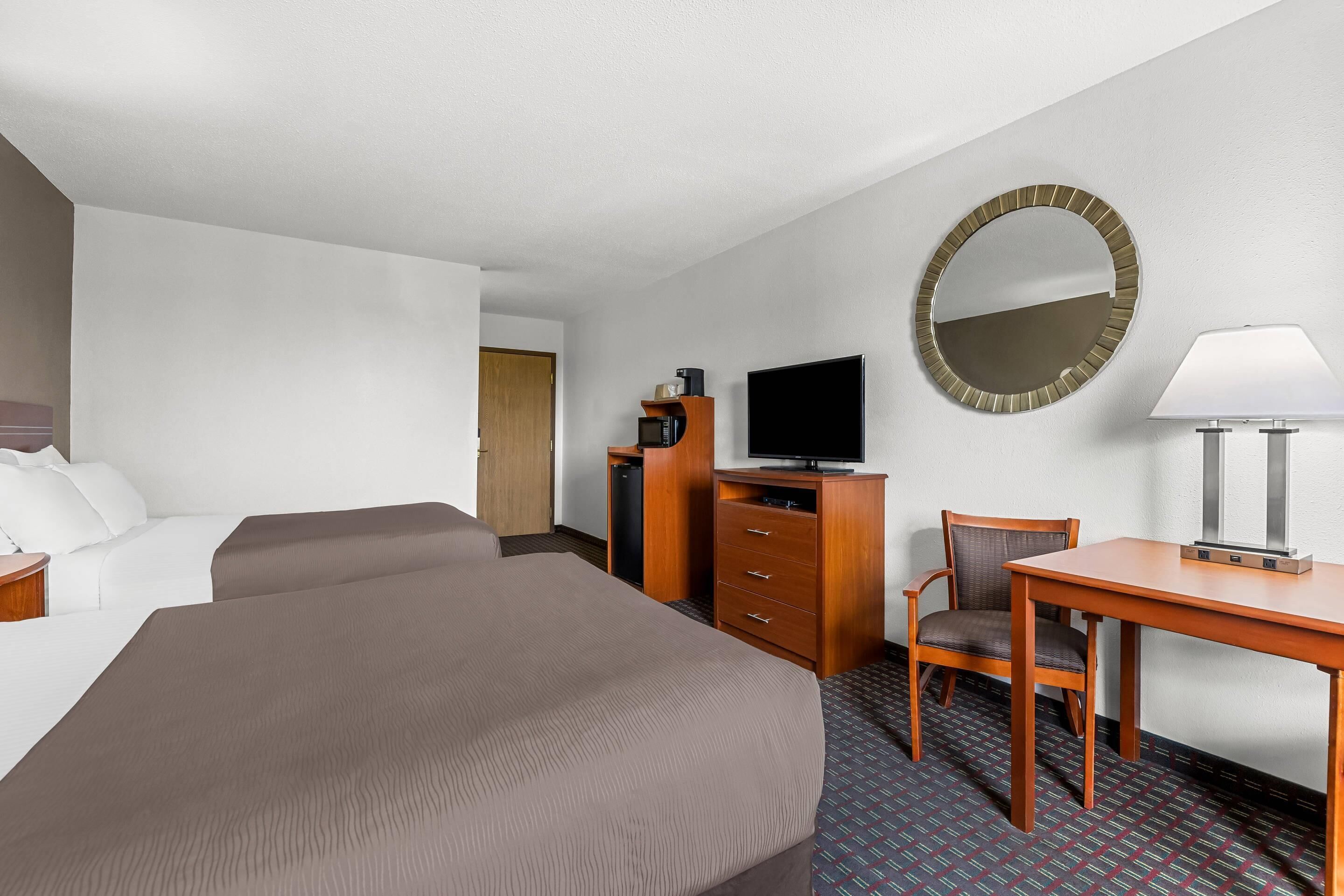 Hotelkamer met een groot bed, een bureau met stoel, een televisie, een spiegel en een kledingkast.