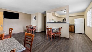 A compact living space with a dining area, kitchen, and a flat-screen TV mounted on the wall. - Rodeway Inn Rapid City North (Rapid City)