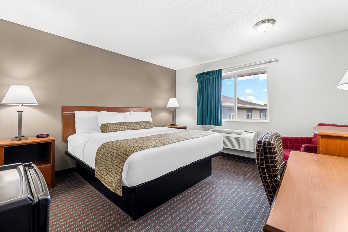 Une chambre d’hôtel avec un grand lit, des tables de chevet, un bureau et une chaise.