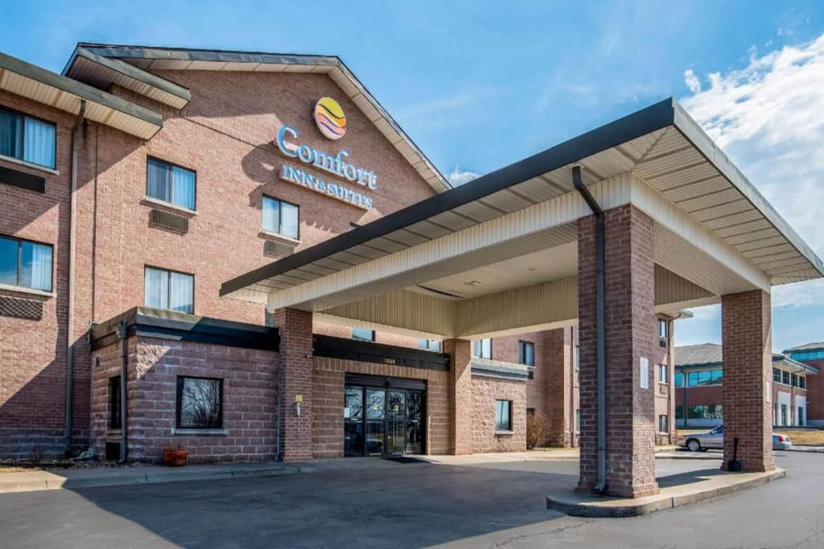 A Comfort Inn & Suites with a brick facade, a covered entrance, and a clear sky.