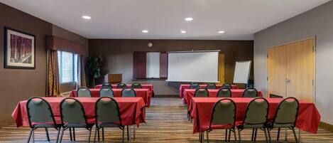 A conference room with tables and chairs, a projector screen, and a presentation screen.