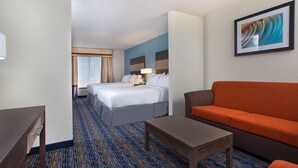 A hotel room with a bed, a sofa, a table, and a painting on the wall. - Holiday Inn Express Berea by IHG (Berea)
