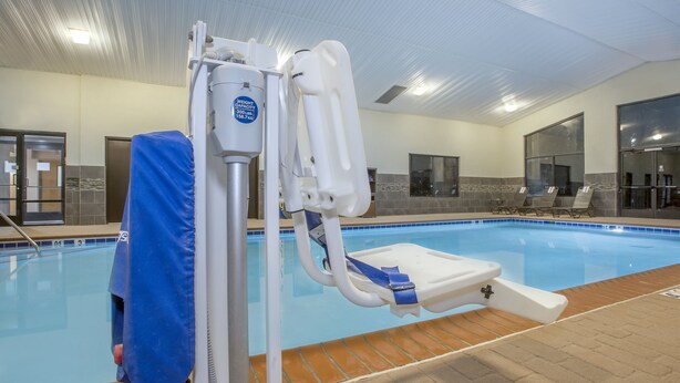 A swimming pool area with a changing station, lounge chairs, and a tiled wall.