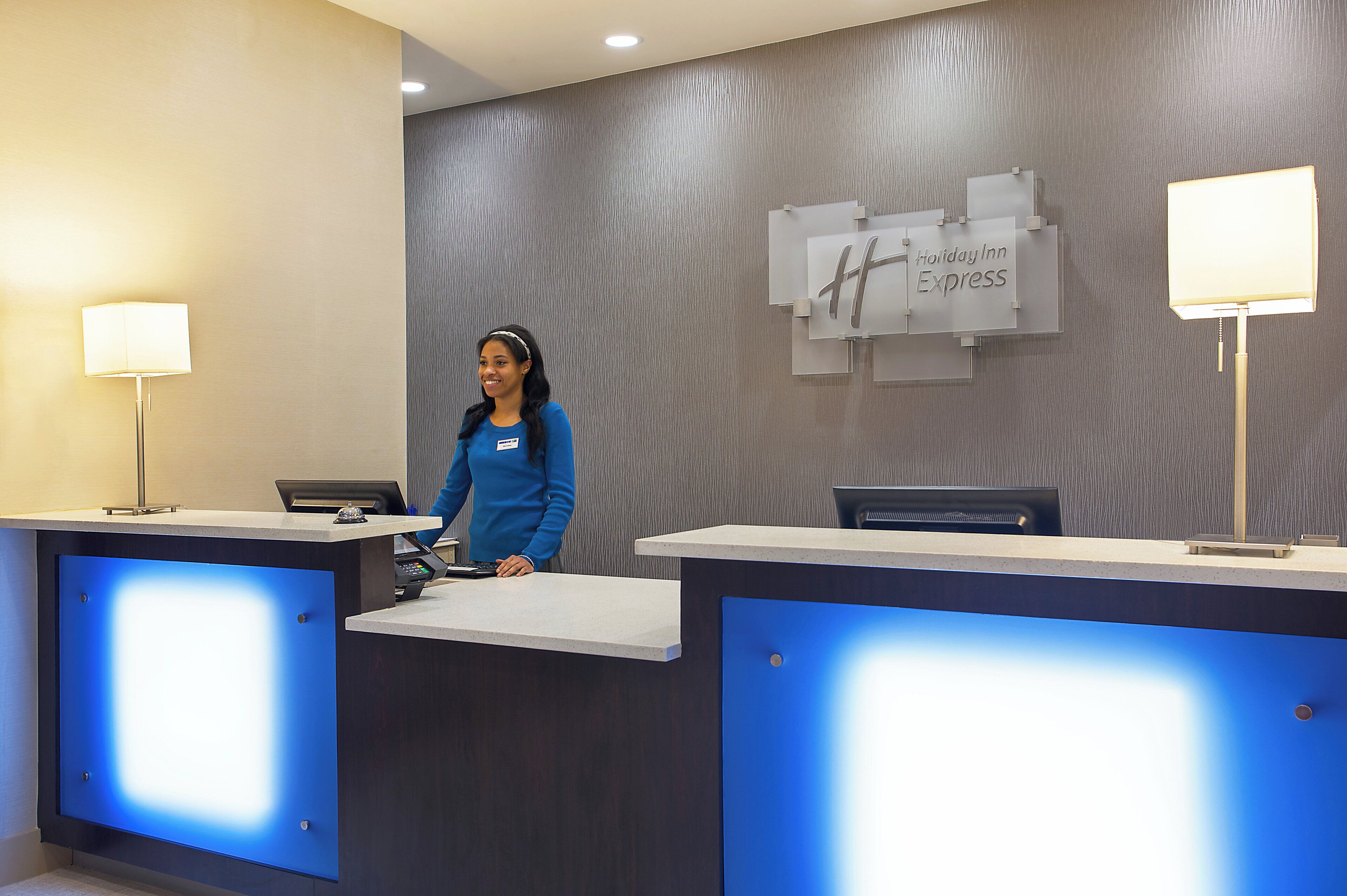 A hotel reception desk with a modern design, a digital display, and a sign for Holiday Inn Express.