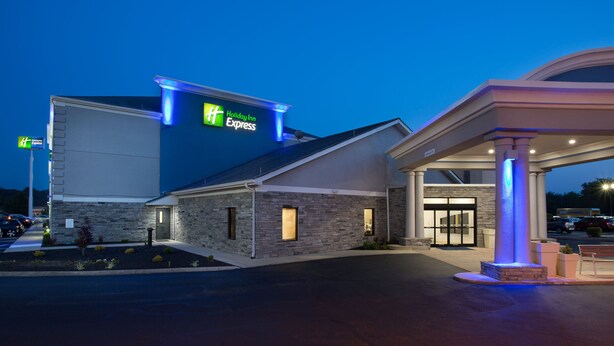 A Holiday Inn Express building with a stone facade, a well-lit entrance, and a gas station with a blue-lit canopy. - Holiday Inn Express Berea by IHG (Berea)