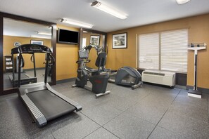 A gym with treadmills, elliptical machines, and a mirrored wall.