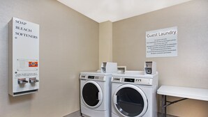 A guest laundry area with two front-loading washing machines, a coin-operated soap, bleach, and softeners dispenser, and a sign indicating guest use only. - Holiday Inn Express Berea by IHG (Berea)