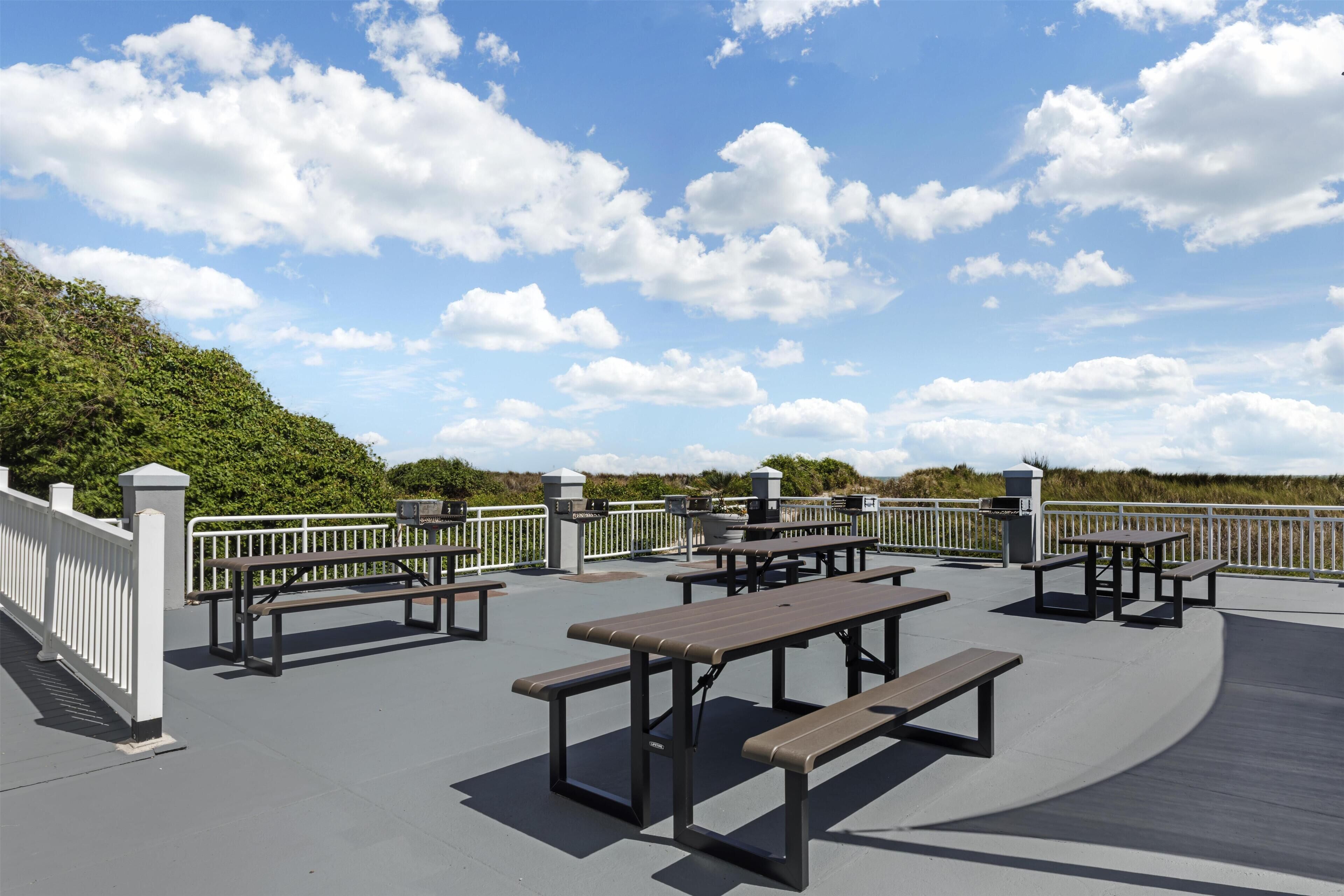 An outdoor patio with picnic tables and a white railing.